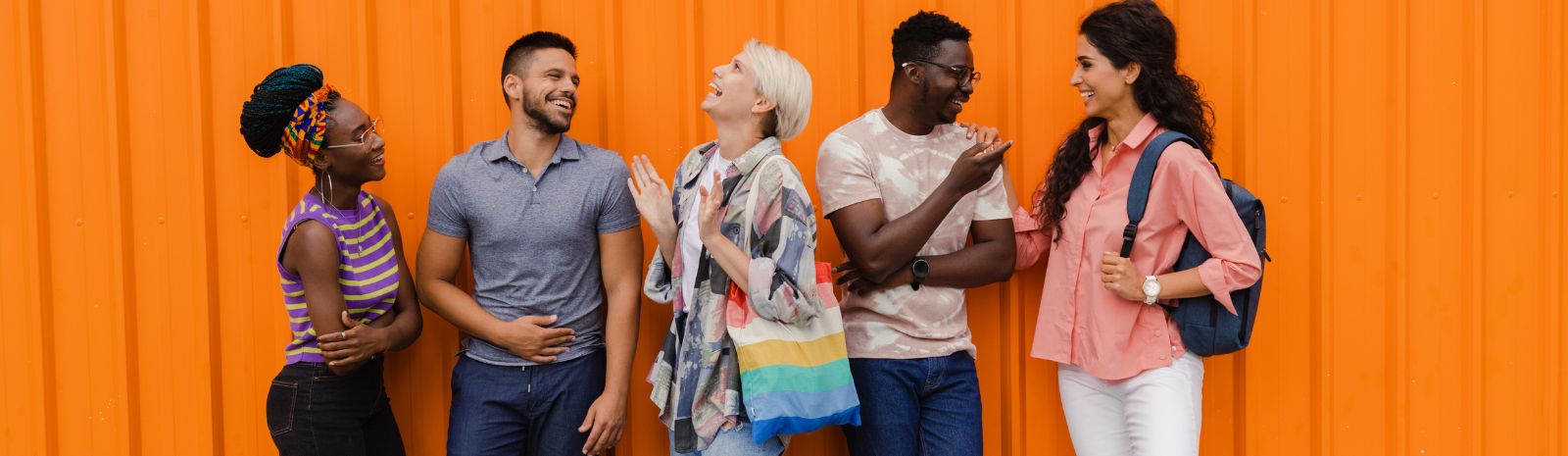 group of people in conversation in front of orange wall