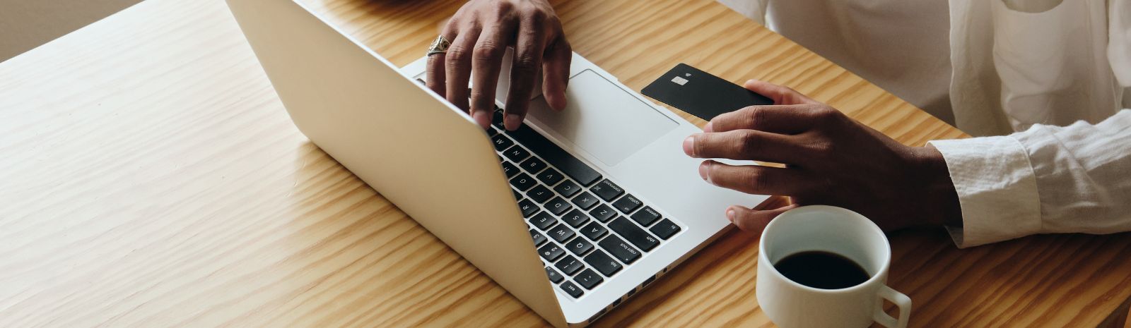 Person at their laptop with their card in front of them with a cup of coffee