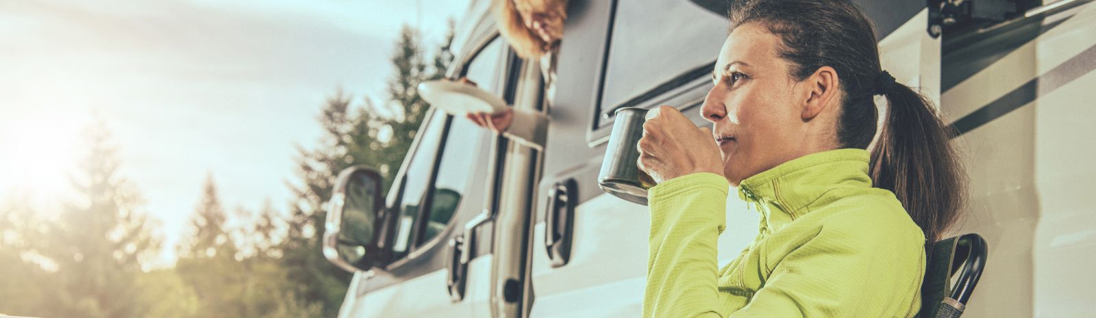 Woman sipping coffee while sitting outside camper
