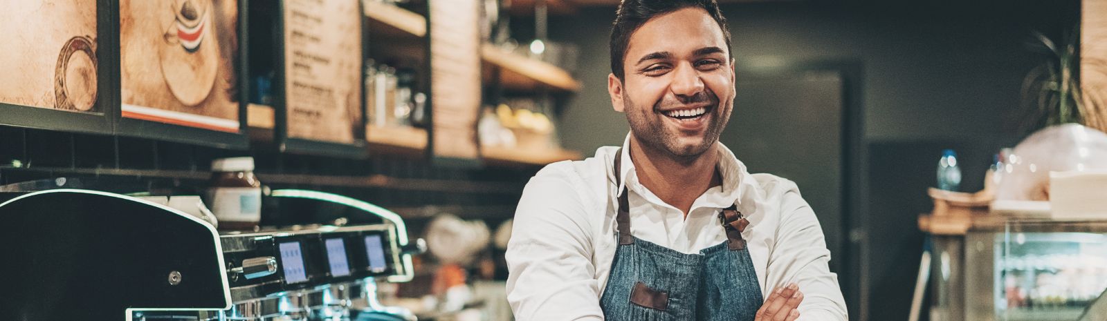 Business owner smiles behind the counter of his coffee shop