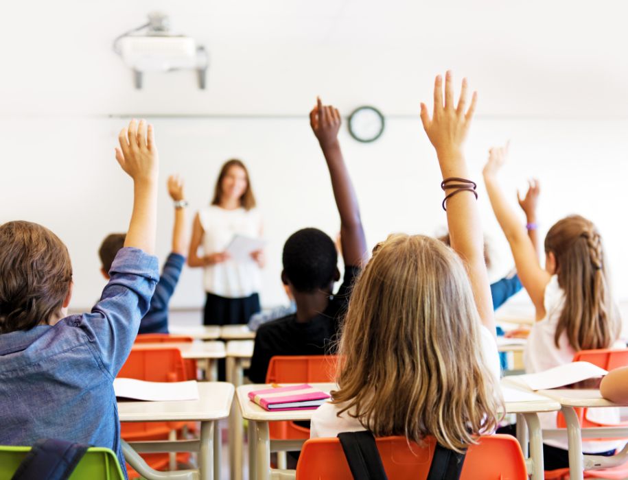 Kids raising their hands in a classroom