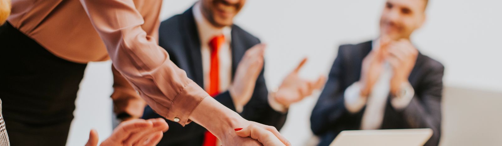 group of professionals sitting around a table with two people shaking hands