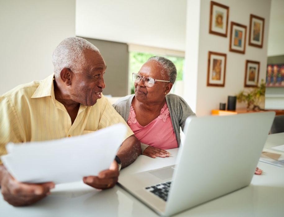 Couple reviewing paperwork at their computer 